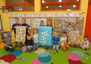 Grupa dzieci stoi z dwoma plakatami prezentującymi Drzewko obowiązków dziecka i jednym plakatem prezentującym Drzewko Praw Dziecka.